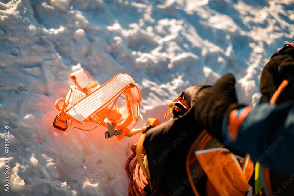 selective focus on bright orange climbing harness on white snow