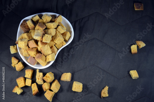 Wheat crackers, heart shaped plate on the table, brown background.
