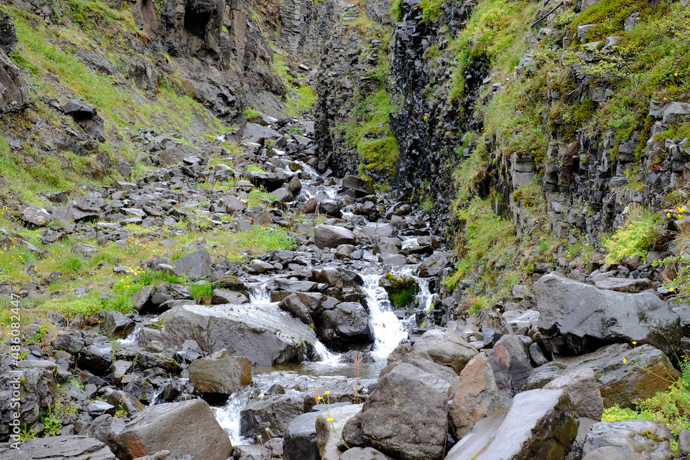 Bach fliesst einen Berghang hinab in das Tal Heydalur Bach fliesst einen Berghang hinab in das Tal Heydalur
