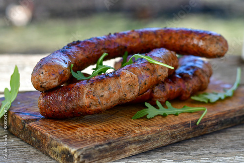 Grilled  pork  juicy sausages on wooden board outdoors. Grilling food, bbq, barbecue, picnic