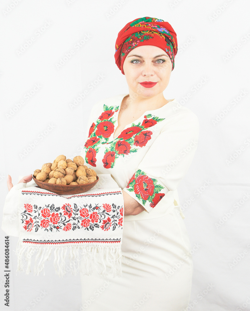 Beautiful ukraine housewife on traditional Ukrainian national clothes holds plate with walnuts on white background Beautiful ukraine housewife on traditional Ukrainian national clothes holds plate with walnuts on white background