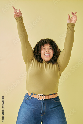 Studio portrait of smiling young woman with arms raised