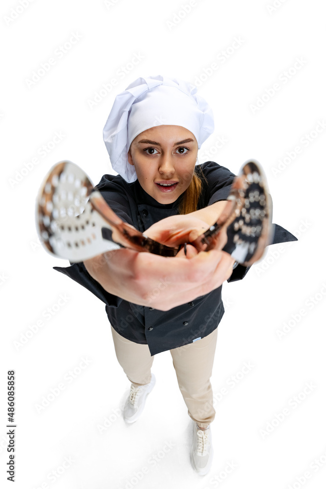 High angle view of beautiful young woman, lady-cook, chef in black uniform isolated on white background. Cuisine, profession, business, food, taste, restaurant concept. High angle view of beautiful young woman, lady-cook, chef in black uniform isolated on white background. Cuisine, profession, business, food, taste, restaurant concept.