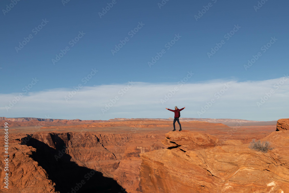 Young man opening arms at horseshoe bend in the grand canyon
