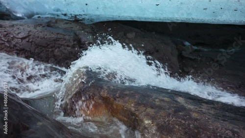 Slow motion shot. Closeup view of the glacier melting stream flowing under the glacier ice field. photo