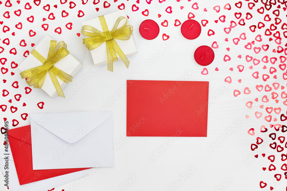 Composition of handmade paper gift boxes, envelopes and candles. Sequins hearts on a white wooden table. Content for Birthday, Valentines Day, Womens day. Flat lay, top view, close up, copy space Composition of handmade paper gift boxes, envelopes and candles. Sequins hearts on a white wooden table. Content for Birthday, Valentines Day, Womens day. Flat lay, top view, close up, copy space