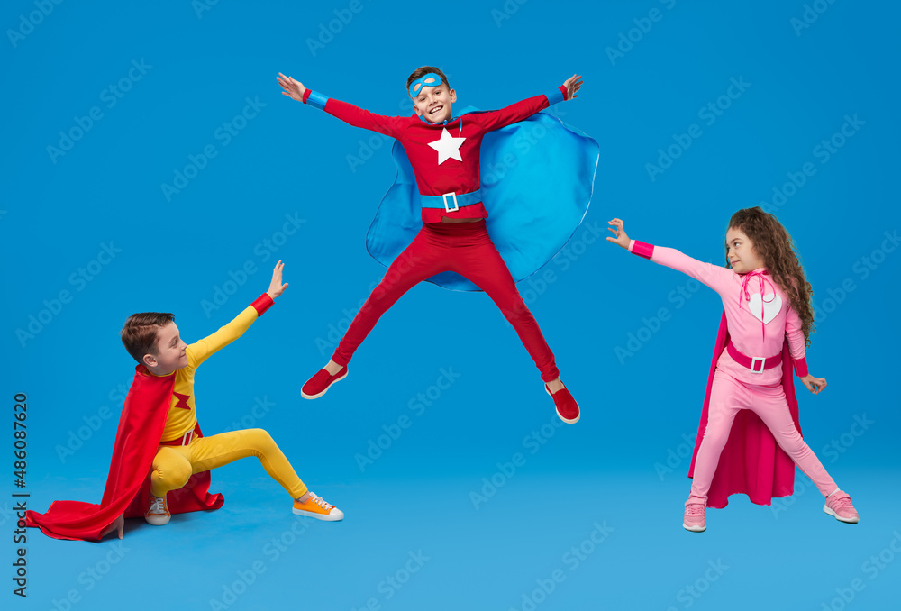 Kids in superhero costumes showing superpowers in studio Kids in superhero costumes showing superpowers in studio