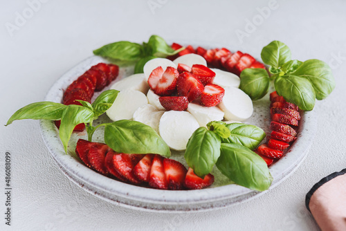 Summer Caprese salad with strawberries. Strawberry salad with basil and mozzarella. Healthy eating concept. Italian cuisine