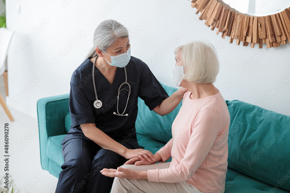 Adult doctor speaking to elderly woman opposite Adult doctor speaking to elderly woman opposite