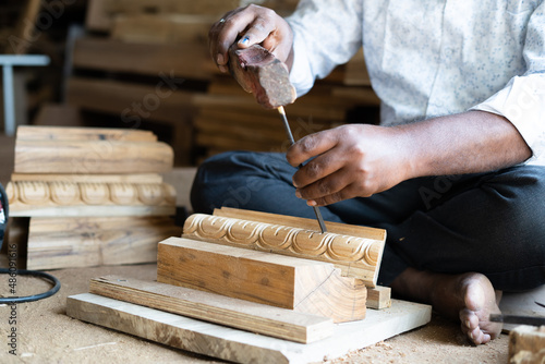 Focus on wood, Close up shot of carpenter hands hitting nail to wood using hammer at schop - concept of workshop, woodworker and craftsman photo