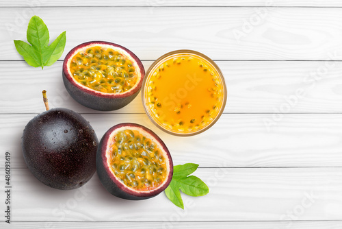 Glass of passion fruit juice (Maracuya} and purple passionfruit with green leaf isolated on white wood background. Top view. Flat lay.