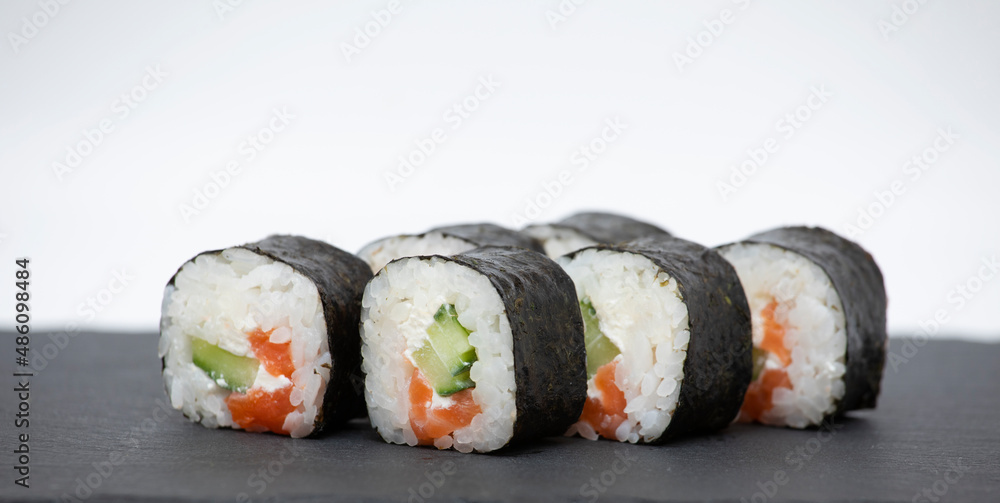 Sushi roll with salmon on a black stand and a white background Sushi roll with salmon on a black stand and a white background
