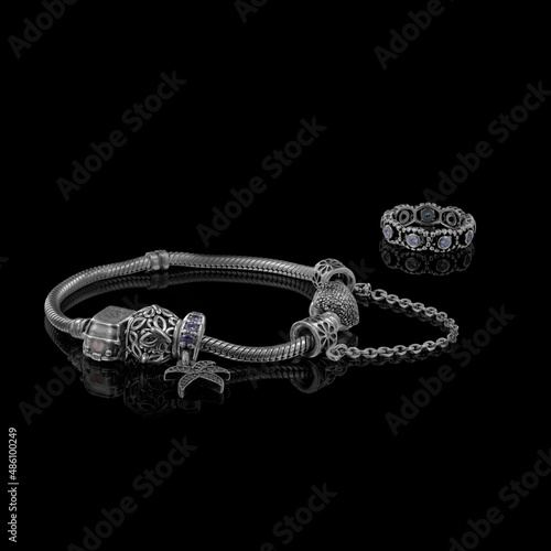 A beautiful, expensive pandora bracelet lies on a table on a black background