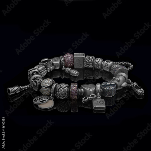 Obraz na płótnie A beautiful, expensive pandora bracelet lies on a table on a black background