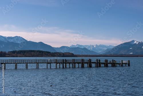 Dampfersteg im Winter am Chiemsee bei Sonnenschein  mit Bergen im Hintergrund