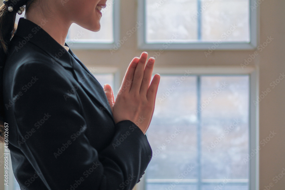 young businesswoman is raising her hands as traditional Thai greeting and saying hello. Raising hands is a beautiful Thai tradition to greet and show respect.concept of friendship, love and kindness young businesswoman is raising her hands as traditional Thai greeting and saying hello. Raising hands is a beautiful Thai tradition to greet and show respect.concept of friendship, love and kindness
