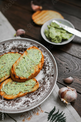 Toasted white bread toast with garlic basil butter on a vintage plate. Morning snacks on the table