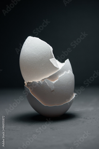 Broken white eggshell on a dark background. The shell is collected in a column.