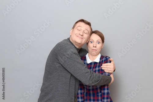 Obraz na plátne Shot of funny couple, happy cheerful man is hugging shocked woman
