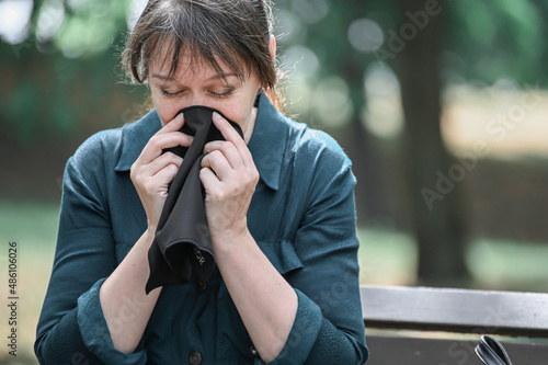 A woman covers her nose with a handkerchief, spring and summer allergies during flowering.