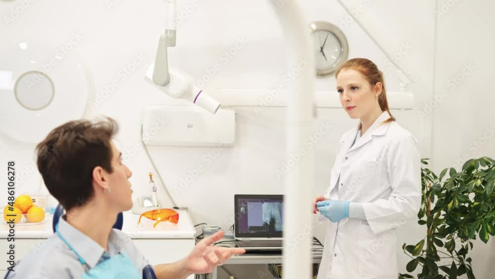 Dentistry consultation. Female dentist discussing dental x-ray with male patient during checkup Dentistry consultation. Female dentist discussing dental x-ray with male patient during checkup