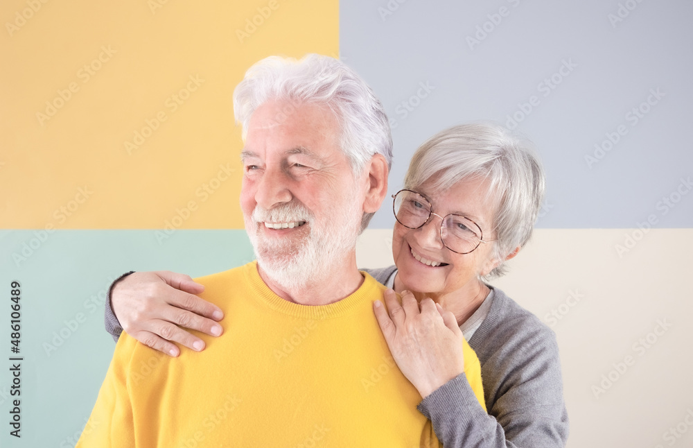 70 years old cute caucasian senior couple standing over isolated colorful background hugging smiling. Portrait of happy lovely white-haired family 70 years old cute caucasian senior couple standing over isolated colorful background hugging smiling. Portrait of happy lovely white-haired family