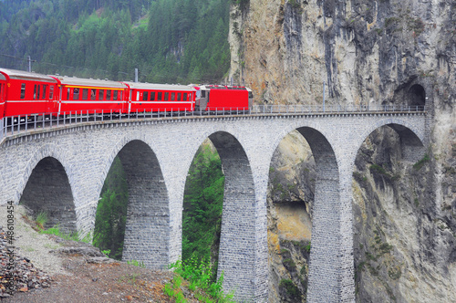 Passenger train goes from Chur to St. Moritz on Landwasser viaduct. Swiss Alps.