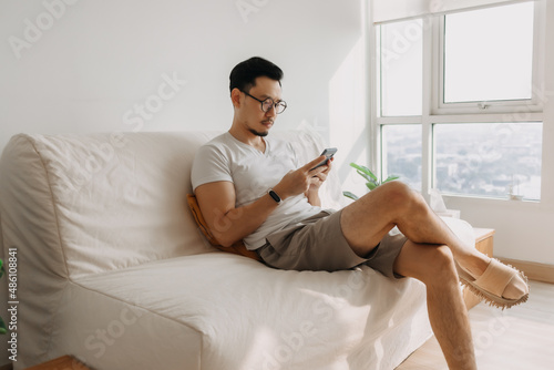 Middle age Asian man with long eye sight try to look at the smartphone.