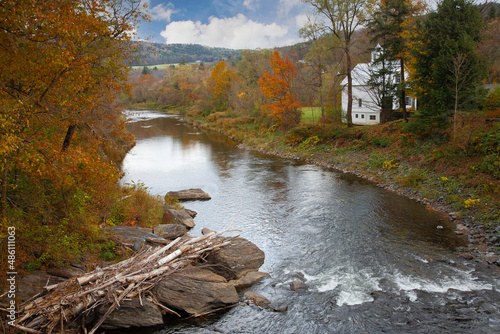 A country church lined with trees showing fall colors beside the Ottauquechee River near Woodstock, Vermont photo