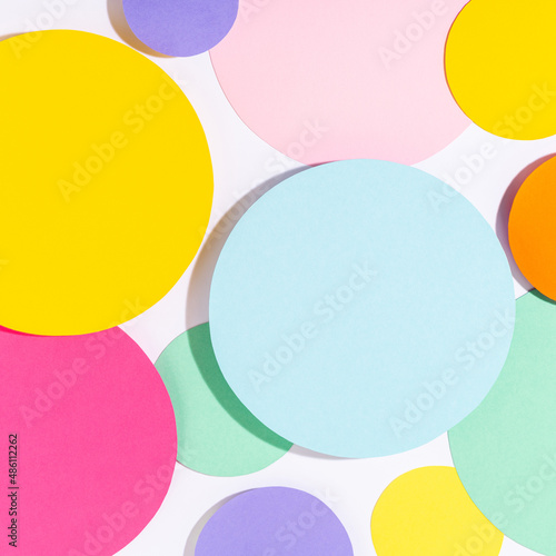 Minimalist round shapes background in pastel pink, blue, yellow and purple colours. Fun bright coloured mosaic of paper circles. Creative conceptual template for styling and design. Mock up for text.