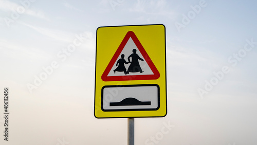 School children crossing sign in qatar along with speed bump sign on the road