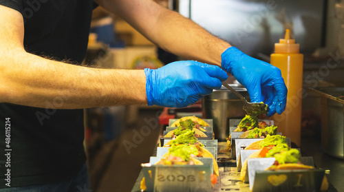 Unrecognizable man putting guacamole in tacos