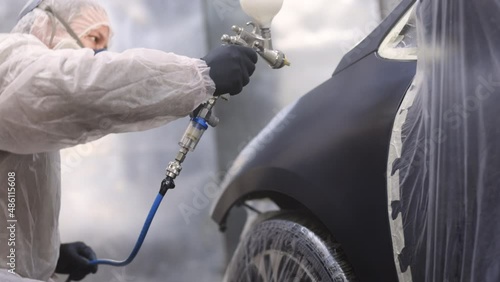 Car manufacturing factory. Painting Spray Paint lacquer vehicle parts at car service workshop. Industrial spray painting process. Man painting a car in a body shop