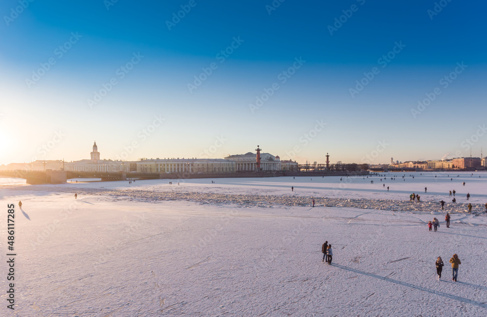 Fototapeta premium Aerial view of walking people on frozen the Neva River in Saint Petersburg at sunny frosty day, Peter and Paul Fortress, Winter Palace, Admiralty, Palace Bridge, Rostral columns