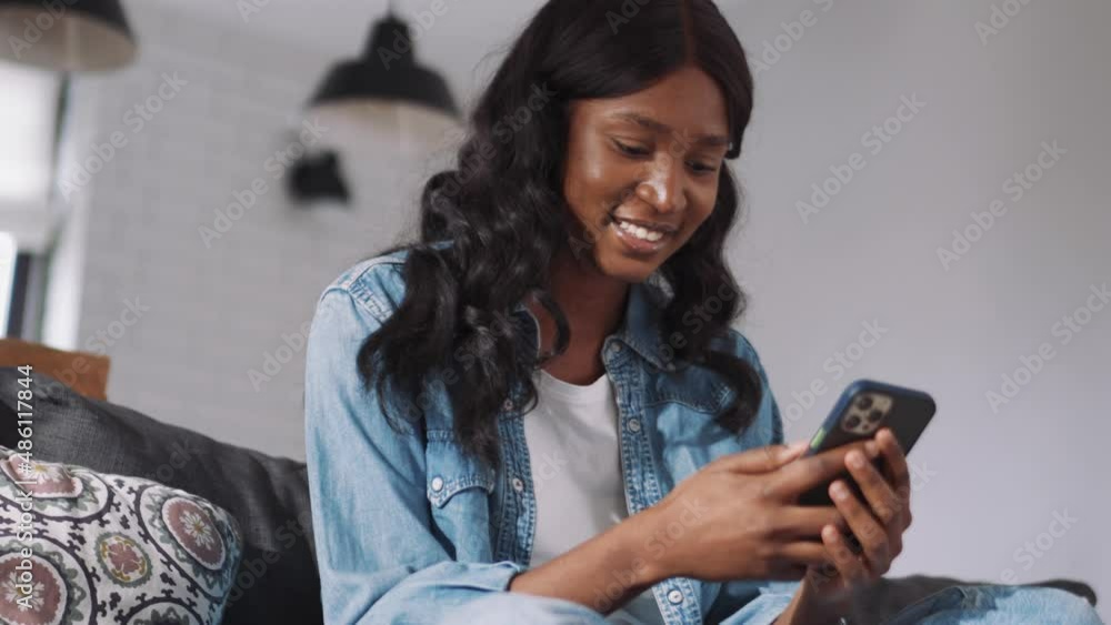 Pretty African woman looking at phone at home Pretty African woman looking at phone at home