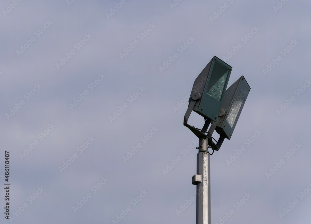 Close-up of a light pole with two lamps with a cloudy sky in the background Close-up of a light pole with two lamps with a cloudy sky in the background