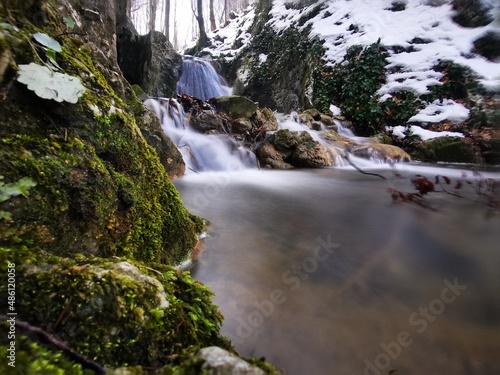 Beautiful mountain stream between rocks  with small waterfall on a snowy winter day © Milje Ivan