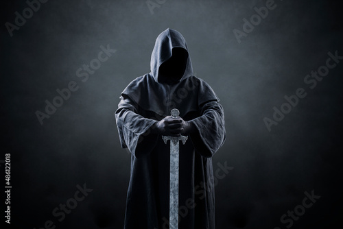 Принти на полотні Warrior with hooded cape and medieval sword over dark misty background