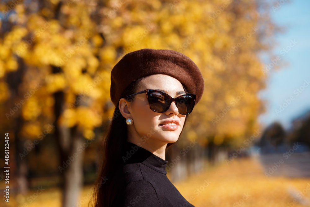 Portrait of sylish woman in brown beret, retro sunglasses, pearl earring outdoor in the park in fall Portrait of sylish woman in brown beret, retro sunglasses, pearl earring outdoor in the park in fall
