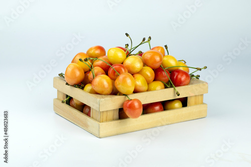 Cherries in box. Sweet yellow rainier cherry in wooden box on white background.