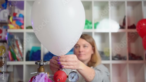 a woman inflates of helium from a white balloon.