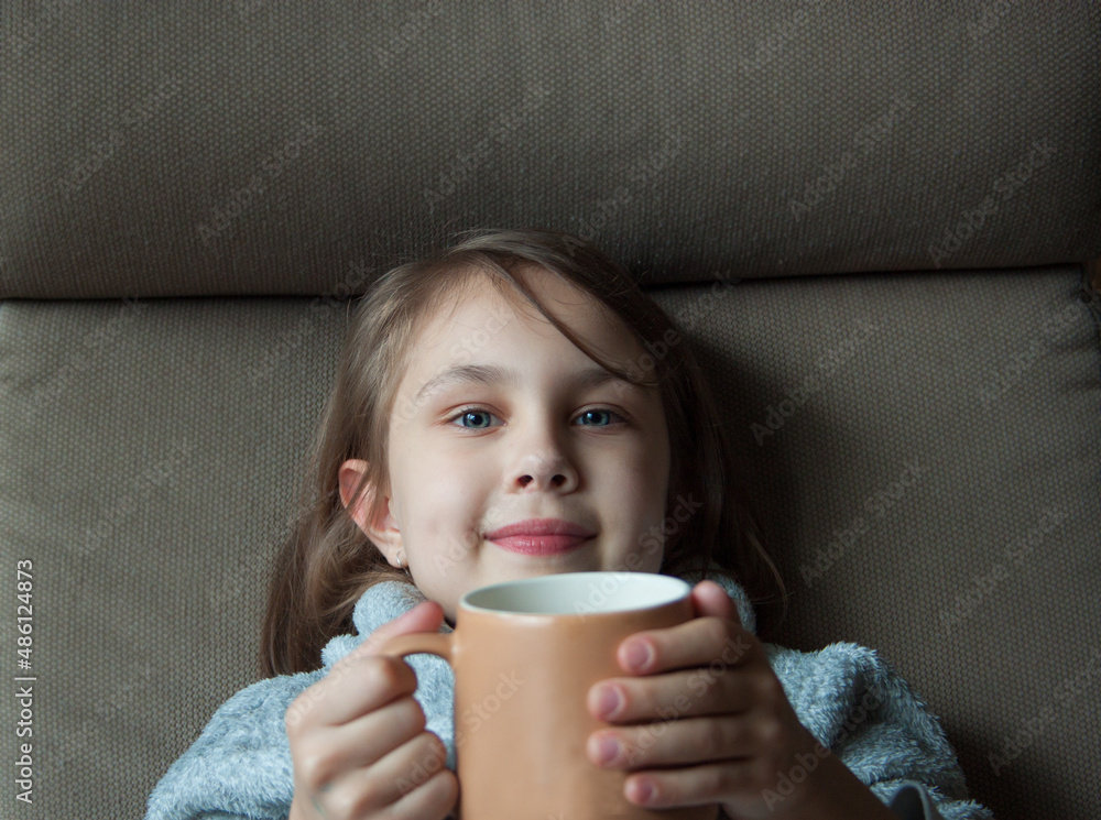 A smiling girl holds out a cup of cocoa. A smiling girl holds out a cup of cocoa.