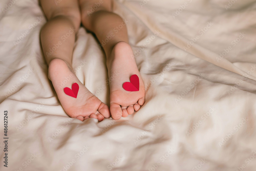 Children's feet and heels with heart on a white bed to Christmas, Valentine's day, Mother's Day. Infant baby is sleeping in his crib. Importance of sleep for babies. Sleep mode babies 3 y.o. Children's feet and heels with heart on a white bed to Christmas, Valentine's day, Mother's Day. Infant baby is sleeping in his crib. Importance of sleep for babies. Sleep mode babies 3 y.o.