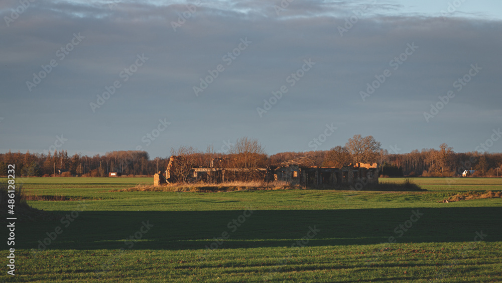 green agricultural field with ruined damaged building without roof green agricultural field with ruined damaged building without roof