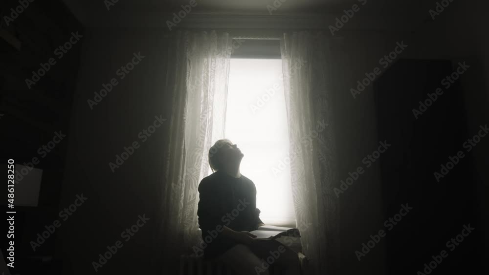 Young handsome white man looking for satisfaction through studying his bible. He is questioning his life in his dimly lit bedroom. The moody cinematic atmosphere, adds tension and mystery. Young handsome white man looking for satisfaction through studying his bible. He is questioning his life in his dimly lit bedroom. The moody cinematic atmosphere, adds tension and mystery.