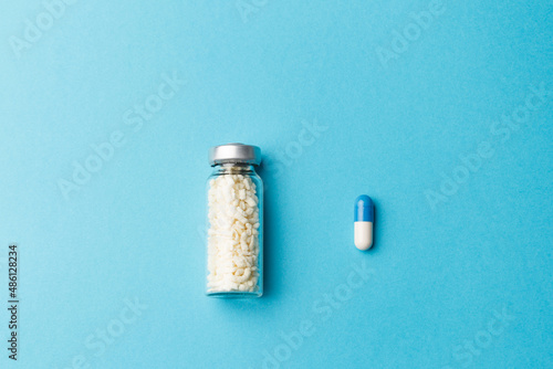 The concept of developing a new drug. A pill with a medicine and a bottle with a new development for the treatment of the disease lie on a blue background. Advertising concept. Top view. Copy space