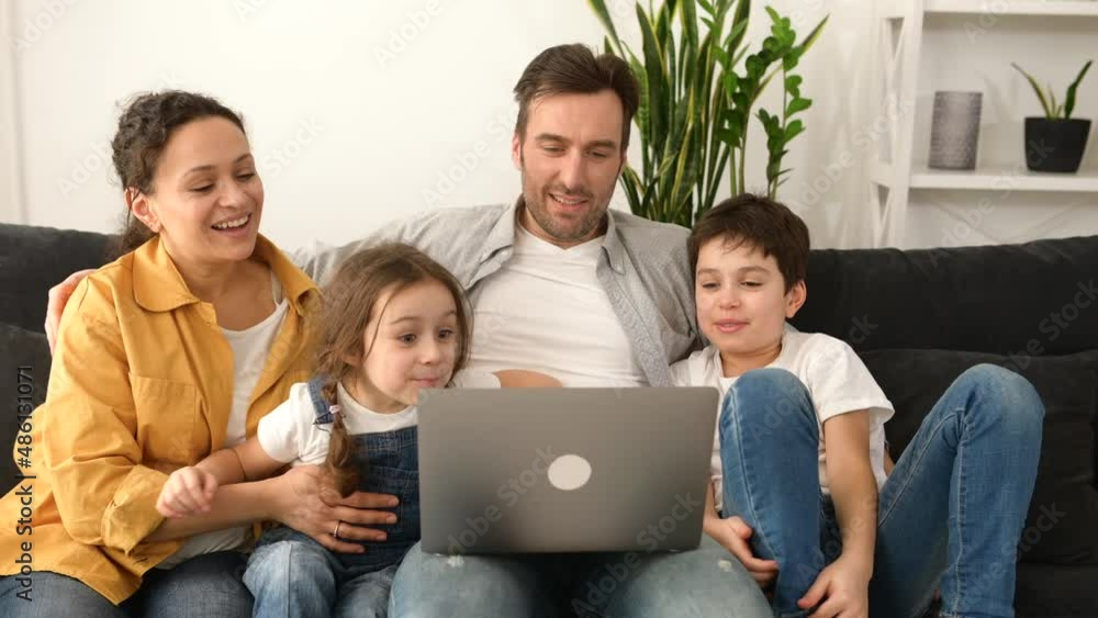 Family of four using laptop for video connection with grandparents or family. Multiracial mom, dad and two kids waving in webcam of the laptop, video call, virtual meeting concept Family of four using laptop for video connection with grandparents or family. Multiracial mom, dad and two kids waving in webcam of the laptop, video call, virtual meeting concept