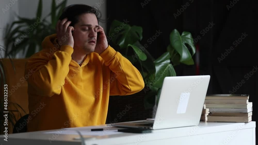 Man working at home office at laptop and listen a music in headphones Man working at home office at laptop and listen a music in headphones