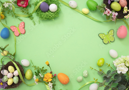Easter flat lay. Egg nest, flower and decoration pastel green background, overhead, space.