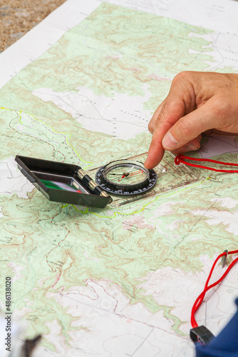 Using a paper map and compass to plot a course of navigation while hiking.